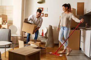 Young couple cleaning an a room full of moving boxes.