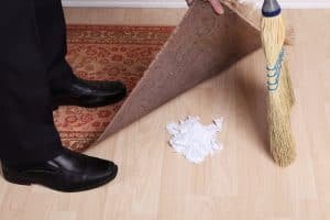 man sweeping dirt under a rug