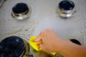 women cleaning stove with washcloth