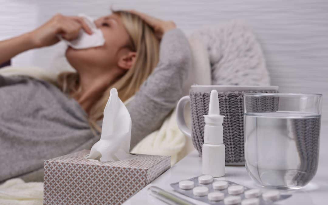 Woman sick in bed with cold or flu, running nose, selective focus on tissue box.