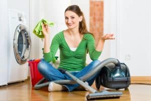 Young woman cleaning at home, she has a cleaning day and using a vacuum cleaner cleaning products and a bucket